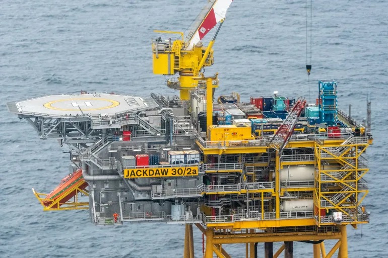 A yellow North Sea oil and gas production platform at sea, its helideck and crane visible