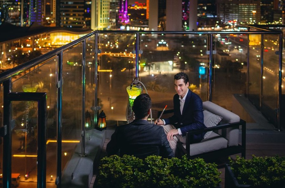 Two men in conversation on a Doha rooftop at night