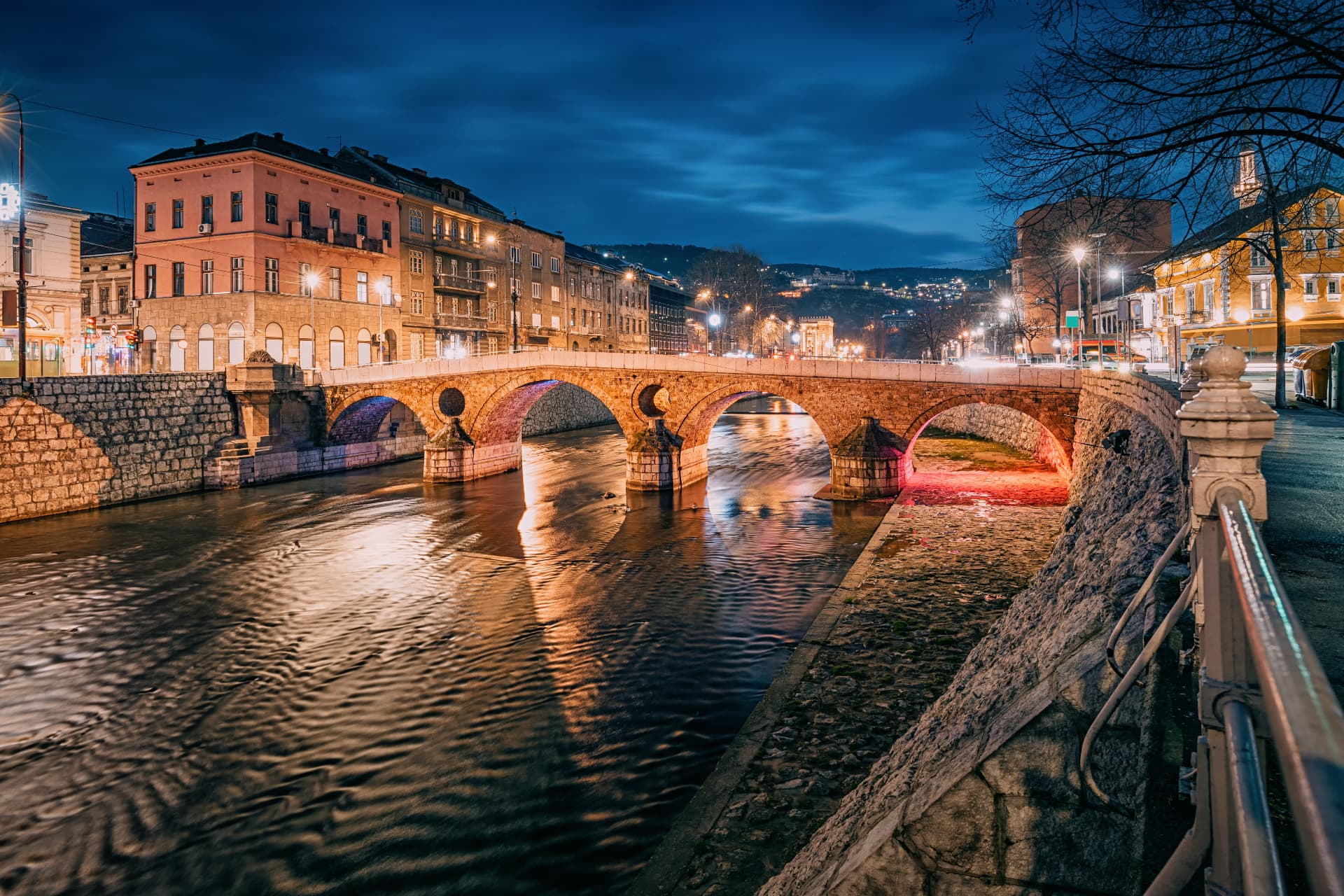 Sarajevo at dusk, the city held in its bowl of mountains, mist rising from the Miljacka